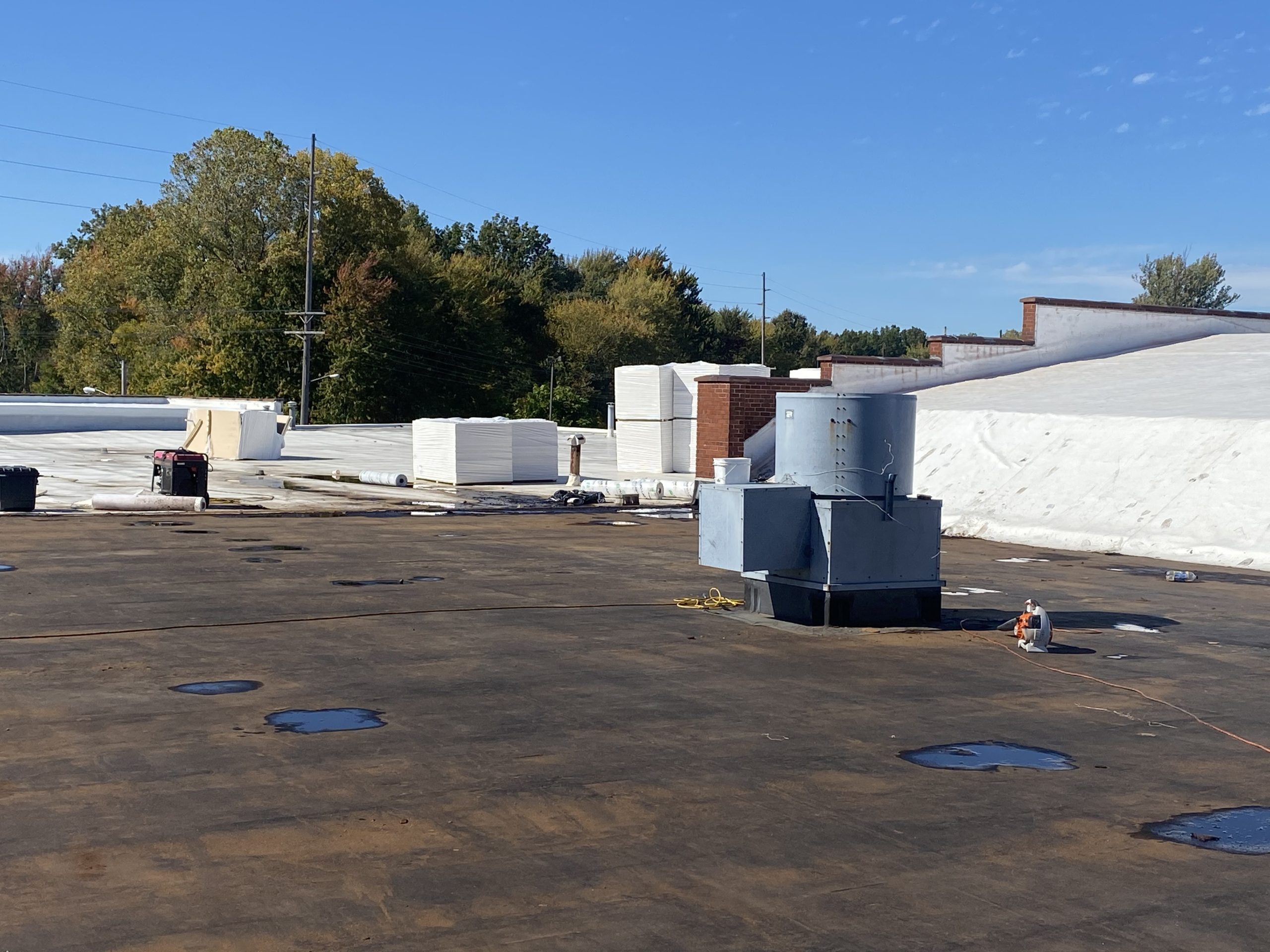 Commercial roof replacement project in progress by Tusing Builders, showing the transition from an old dark substrate to a new white membrane system as part of commercial roof maintenance in Akron.