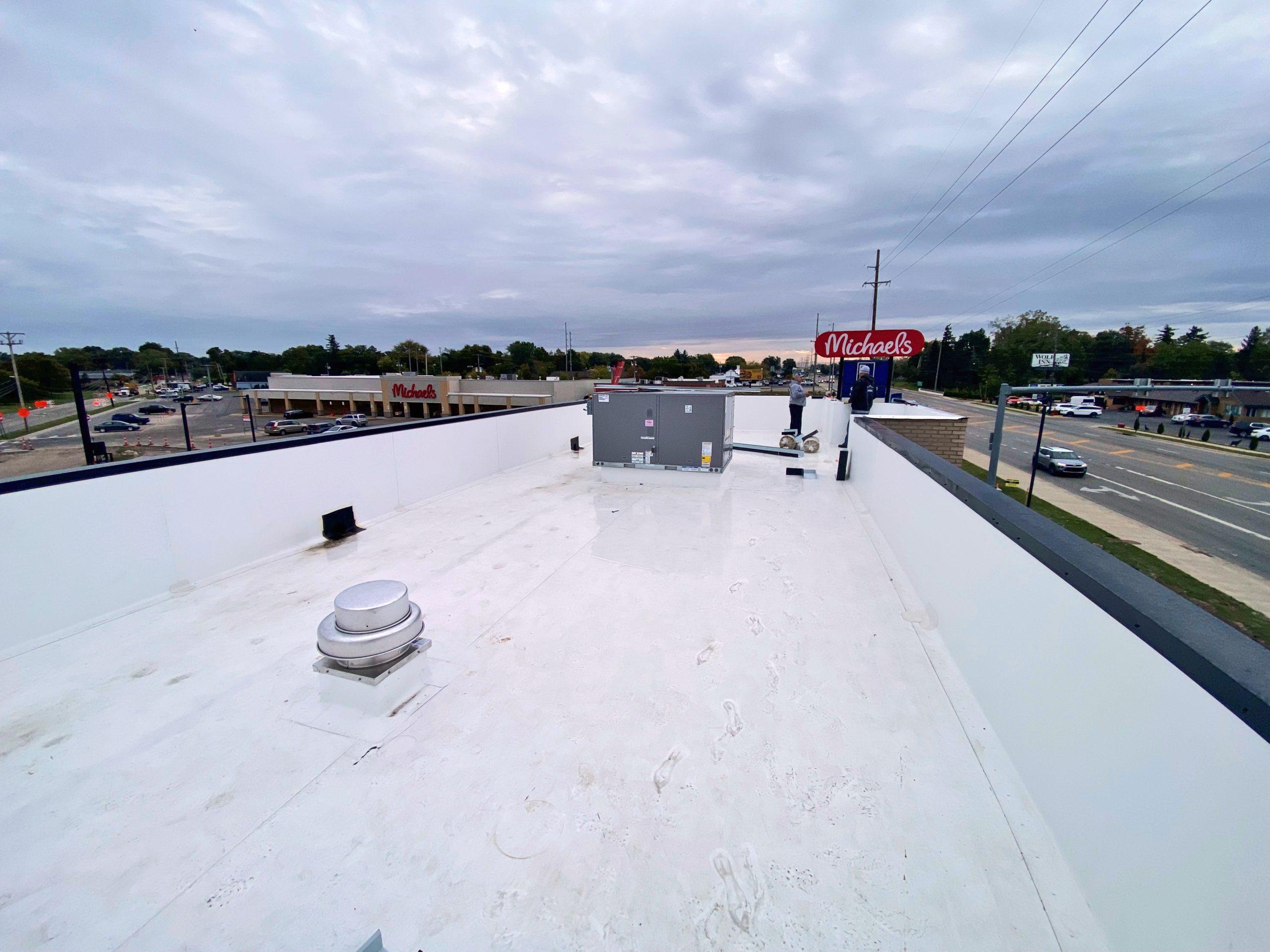 Technical field photo of a newly completed high-performance commercial roofing system in Akron, OH by Tusing Builders, featuring a monolithic white membrane with precision detailing around industrial HVAC units, parapet walls, and exhaust vents on a retail facility.